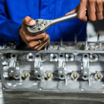 Mechanic repairing an engine part with a ratchet