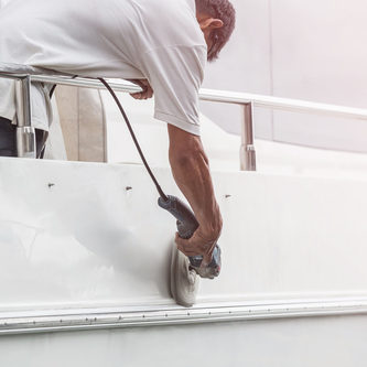 Man polishing the side of a white boat